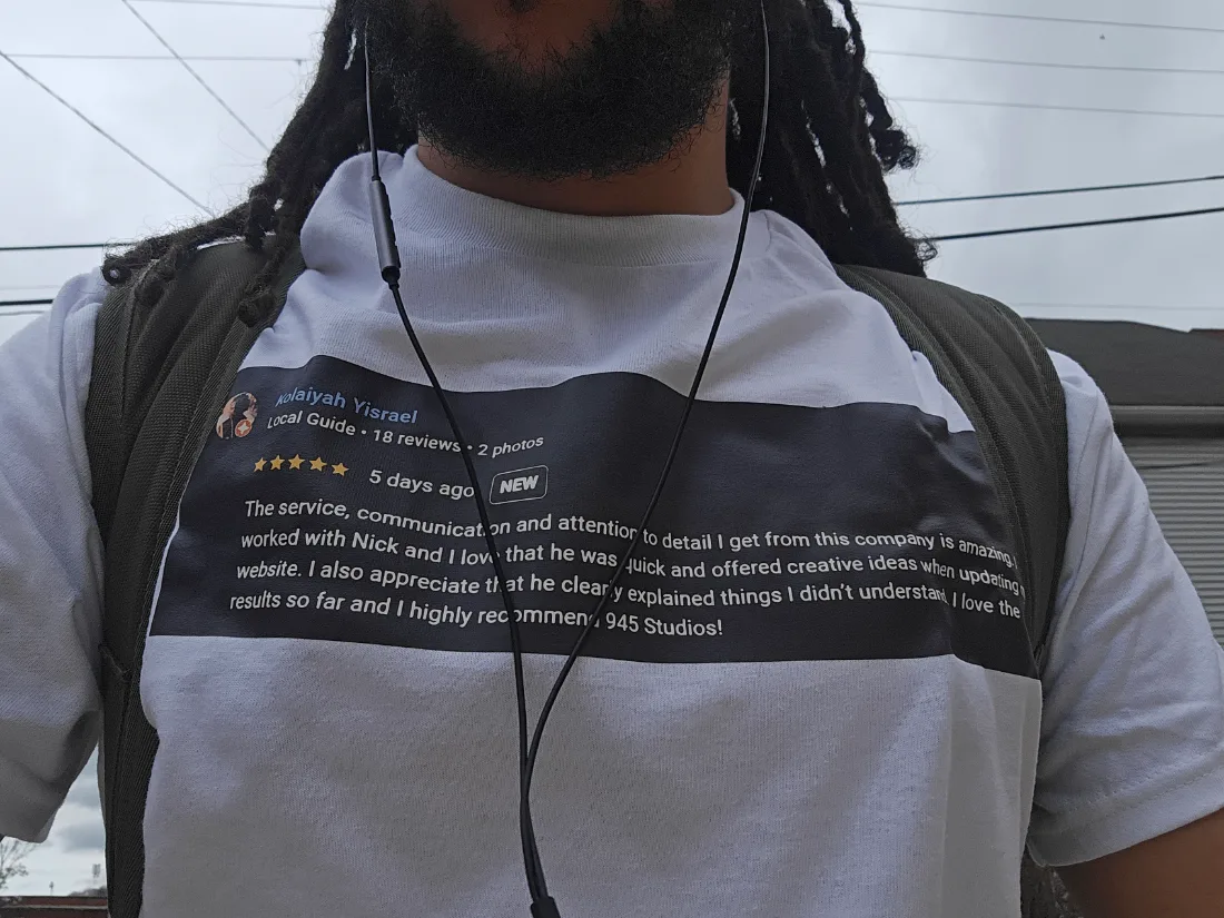 Nick Lookabaugh wearing a white t-shirt printed with a five star Google review from Kolaiyah Yisrael that recommends 945 Studios.